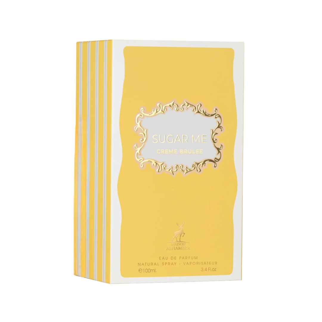 Maison Alhambra Sugar Me Creme Brulee — A clear glass perfume bottle with a gold cap and a yellow and gold decorative front, next to its yellow and white striped box with a decorative gold frame containing the product name. | Maison Alhambra Sugar Me Creme Brulee — Botol minyak wangi kaca jernih dengan penutup emas