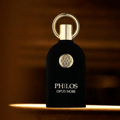 Maison Alhambra Philos Opus Noir by Maison Alhambra 100ml EDP — A black perfume bottle with a gold ring cap and a circular gold emblem on the front, next to its matching black and gold box with the same emblem and text. | Maison Alhambra Philos Opus Noir by Maison Alhambra 100ml EDP — Botol minyak wangi hitam dengan