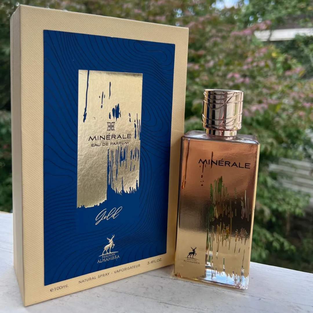 Maison Alhambra Minerale Gold by Maison Alhambra 100ml EDP — A gold-colored perfume bottle and its matching yellow and blue box are displayed side-by-side against a white background. | Maison Alhambra Minerale Gold by Maison Alhambra 100ml EDP — Botol minyak wangi berwarna emas dan kotak padanannya yang berwarna