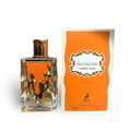Maison Alhambra Sugar Me Carrot Cake — A clear glass perfume bottle with an orange liquid and gold decorative elements, next to its orange and white striped box with a gold ornate frame containing the product name. | Maison Alhambra Sugar Me Carrot Cake — Botol minyak wangi kaca jernih dengan cecair oren dan elemen