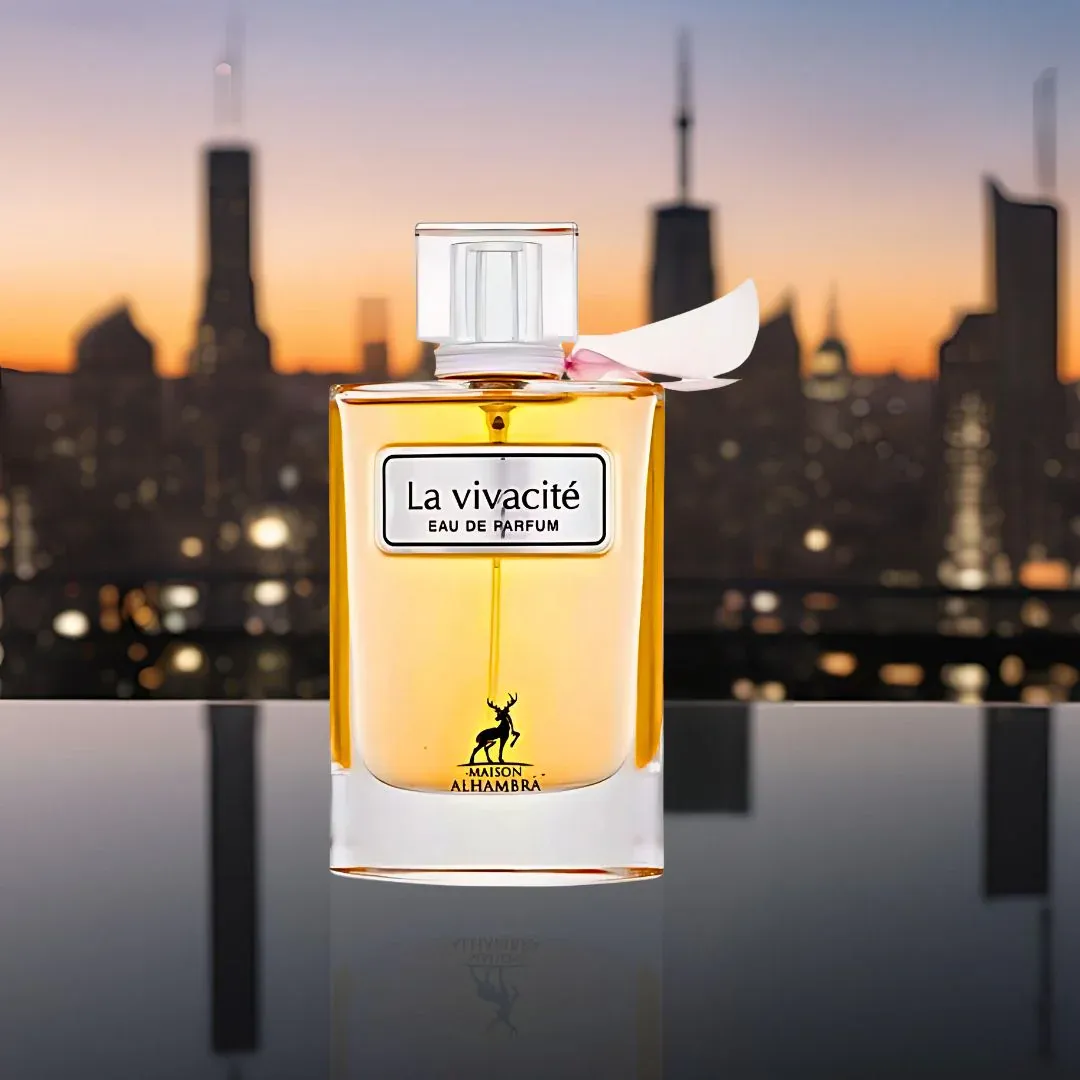 Maison Alhambra La Vivacite by Maison Alhambra 100ml EDP — A perfume box with a pink glitter design and a glass perfume bottle with golden liquid and a pink ribbon accent, displayed on a white background. | Maison Alhambra La Vivacite by Maison Alhambra 100ml EDP — Kotak minyak wangi dengan rekaan kilauan merah jambu