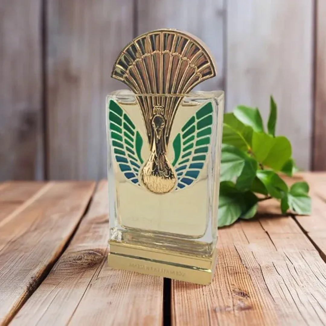 Maison Alhambra La Charmante by Maison Alhambra 100ml EDP — A perfume bottle with a gold and green peacock-inspired cap and ornate detailing on the front, displayed next to its matching dark teal box with art deco-inspired patterns and a deer emblem. | Maison Alhambra La Charmante by Maison Alhambra 100ml EDP — Botol