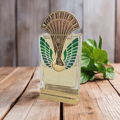 Maison Alhambra La Charmante by Maison Alhambra 100ml EDP — A perfume bottle with a gold and green peacock-inspired cap and ornate detailing on the front, displayed next to its matching dark teal box with art deco-inspired patterns and a deer emblem. | Maison Alhambra La Charmante by Maison Alhambra 100ml EDP — Botol