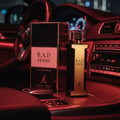 B.A.D. Femme by Maison Alhambra — A perfume bottle and its box are placed on the dashboard of a car at night, with red ambient lighting. | B.A.D. Femme by Maison Alhambra — Botol minyak wangi dan kotaknya diletakkan di papan pemuka kereta pada waktu malam, dengan pencahayaan ambien merah.
