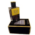 Maison Alhambra B.A.D. Homme — A black and gold perfume bottle stands tilted on its matching black and gold box, with the cap facing upwards. | Maison Alhambra B.A.D. Homme — Botol minyak wangi hitam dan emas berdiri condong di atas kotak hitam dan emas yang sepadan, dengan penutup menghadap ke atas.
