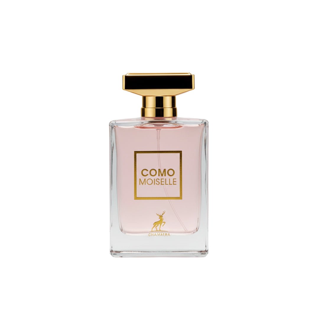Maison Alhambra Como Moiselle by Maison Alhambra 100ml for Her — A clear glass perfume bottle with light pink liquid, a gold cap, and a gold label featuring the text "COMO MOISELLE" and a deer silhouette. | Maison Alhambra Como Moiselle by Maison Alhambra 100ml for Her — Botol minyak wangi kaca jernih dengan cecair