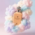 Maison Alhambra Decadent Wonder Her EDP 100 ml Alhambra — A peach-colored perfume bottle is surrounded by fluffy, pastel-colored clouds against a gradient background. | Maison Alhambra Decadent Wonder Her EDP 100 ml Alhambra — Botol minyak wangi berwarna pic dikelilingi oleh awan gebu berwarna pastel dengan latar