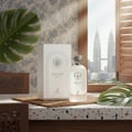Maison Alhambra Delilah Blanc by Maison Alhambra 100ml EDP — A white perfume bottle and its box sit on a speckled countertop next to a large monstera leaf, with a blurred cityscape featuring twin skyscrapers visible through a window with wooden shutters. | Maison Alhambra Delilah Blanc by Maison Alhambra 100ml EDP —