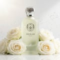 Maison Alhambra Delilah Blanc by Maison Alhambra 100ml EDP — A frosted glass perfume bottle with a silver ornate cap, surrounded by white roses and gold glitter against a white background. | Maison Alhambra Delilah Blanc by Maison Alhambra 100ml EDP — Botol kaca beku dengan penutup perak berhias, dikelilingi mawar