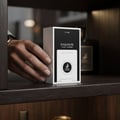 Maison Alhambra Exquisite Club By Maison Alhambra For Men 100ml — A hand is reaching for a perfume box on a shelf, with another bottle in the background. | Maison Alhambra Exquisite Club By Maison Alhambra For Men 100ml — Tangan sedang mencapai kotak minyak wangi di atas rak, dengan botol lain di latar belakang.