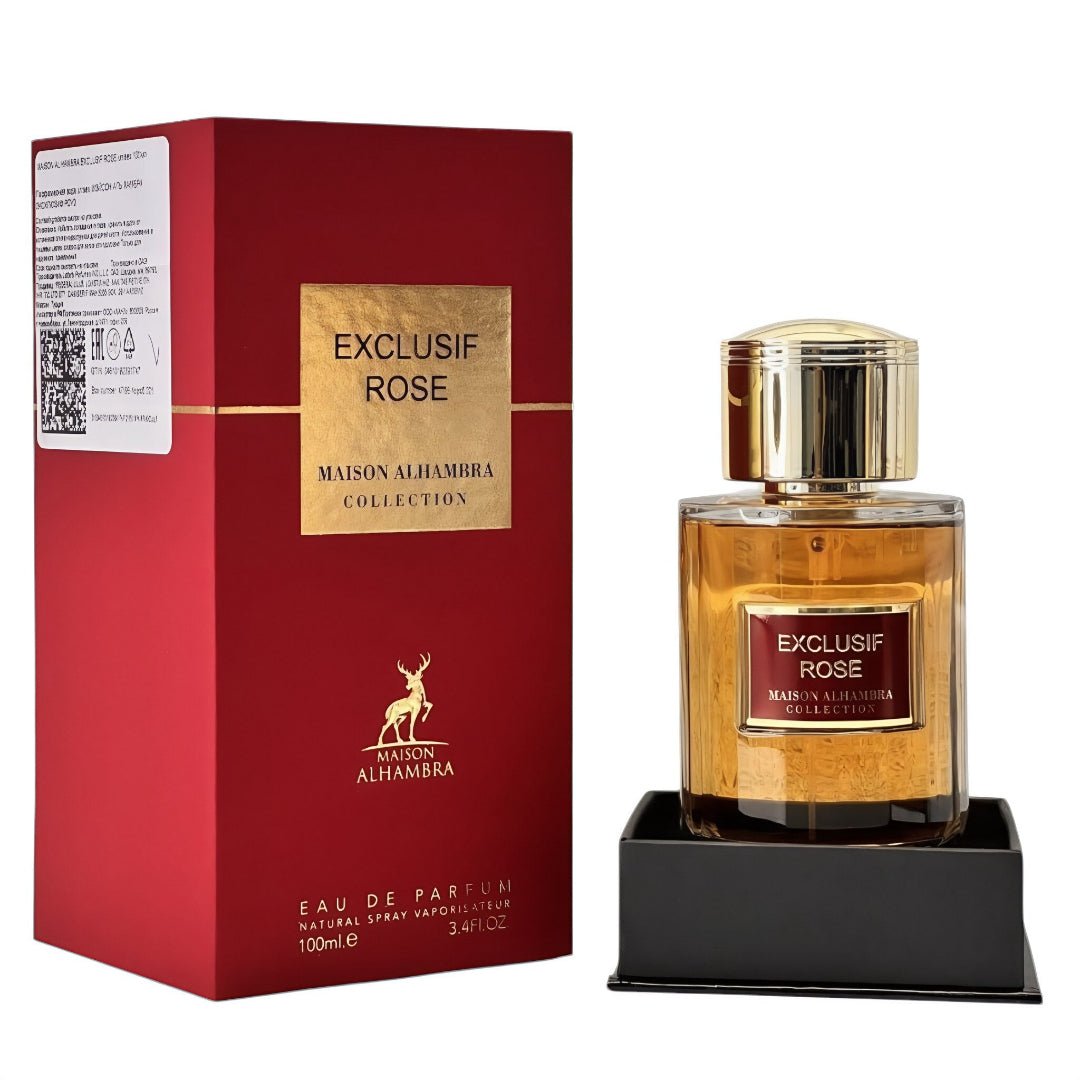 Maison Alhambra Exclusif Rose — A red box and a glass perfume bottle with gold accents, both featuring the 'Exclusif Rose' label. The bottle contains amber-colored liquid and sits on a black stand. | Maison Alhambra Exclusif Rose — Peti merah dan botol minyak wangi kaca dengan aksen emas, kedua-duanya mempunyai label