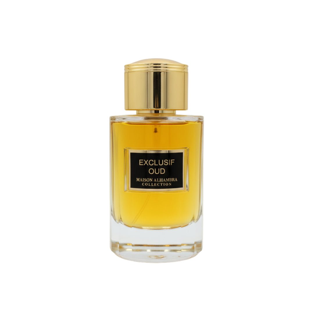 Maison Alhambra Exclusif Oud — A clear glass perfume bottle with golden cap and a black label reading "EXCLUSIF OUD MAISON ALHAMBRA COLLECTION". The liquid inside is amber-colored. | Botol minyak wangi kaca jernih dengan penutup emas dan label hitam bertuliskan "EXCLUSIF OUD MAISON ALHAMBRA COLLECTION". Cecair di