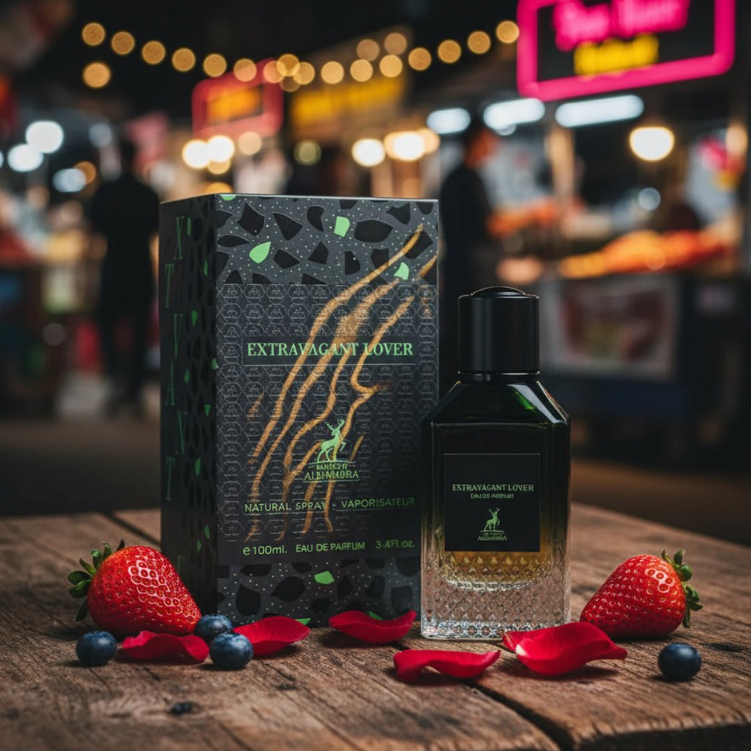 Extravagant Lover by Maison Alhambra – 100 ml – A perfume bottle and its box sit on a wooden surface with strawberries, blueberries, and rose petals scattered around. The background is a blurred night market with bokeh lights. | Extravagant Lover oleh Maison Alhambra – 100 ml – Botol minyak wangi dan kotaknya