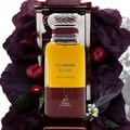 Maison Alhambra Flaming Elixir — A bottle of amber and burgundy Eau de Parfum stands next to its matching burgundy box with a white label. | Maison Alhambra Flaming Elixir — Sebotol Eau de Parfum berwarna kuning dan burgundy berdiri di sebelah kotak burgundy yang sepadan dengan label putih.