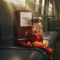 Maison Alhambra Forbidden Love by Maison Alhambra 80ml EDP Women — A perfume bottle and its box are displayed on a dark surface, surrounded by fresh strawberries, cherries, and orange slices, with a blurred train interior in the background. | Maison Alhambra Forbidden Love by Maison Alhambra 80ml EDP Women — Botol