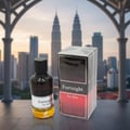 Maison Alhambra Fortnight by Maison Alhambra 100ml EDP Men — A dark glass perfume bottle with a white label and a clear box sit on a reflective surface with a blurred city skyline and iconic towers in the background. | Maison Alhambra Fortnight by Maison Alhambra 100ml EDP Men — Sebotol minyak wangi kaca gelap dengan