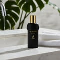 Maison Alhambra Glacier Le Noir — Black perfume bottle with gold cap on a marble countertop with water splashing from a faucet and white towels stacked | Maison Alhambra Glacier Le Noir — Botol minyak wangi hitam dengan penutup emas di atas meja marmar dengan percikan air dari pili dan tuala putih bertindan