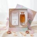 Maison Alhambra Glossy By Maison Alhambra 100ml Women EDP — A gift set featuring a bottle of Glossy perfume and its matching box, presented in an open decorative box with a pink ribbon and gold filigree accents, surrounded by pearls and dried roses. | Maison Alhambra Glossy By Maison Alhambra 100ml Women EDP — Set