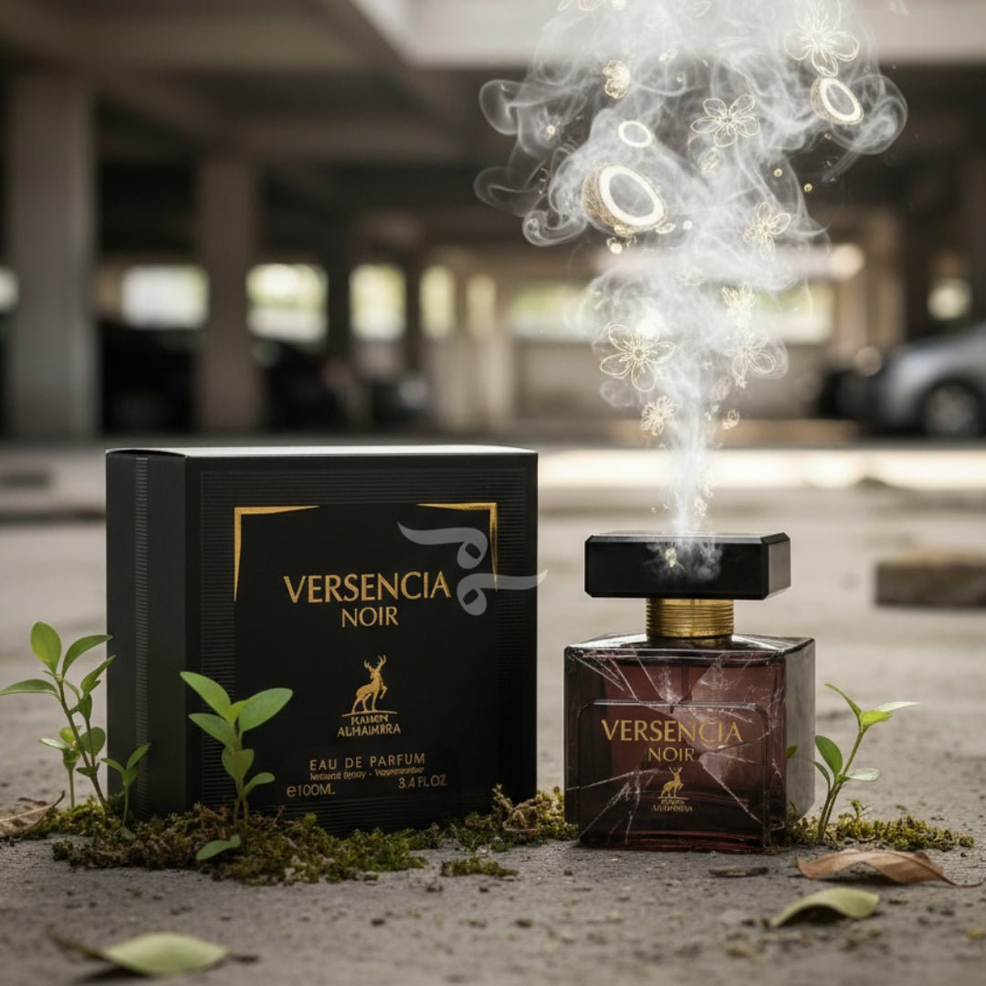 Maison Alhambra Versencia Noir – Black box and dark glass bottle with smoke and floral elements rising from the bottle, set on a concrete surface with moss and small plants. | Maison Alhambra Versencia Noir – Kotak hitam dan botol kaca gelap dengan asap dan elemen bunga naik dari botol, diletakkan di permukaan konkrit