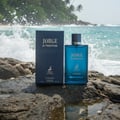 Maison Alhambra Jorge Di Profondo Deep Blue — A blue glass perfume bottle and its dark blue box sit on wet rocks with ocean waves crashing in the background. | Maison Alhambra Jorge Di Profondo Deep Blue — Botol kaca biru dan kotak biru gelapnya diletakkan di atas batu basah dengan ombak laut berderu di latar belakang.