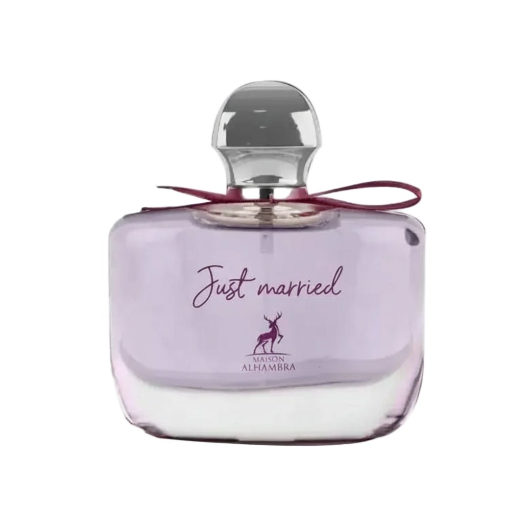 Maison Alhambra Just Married by Maison Alhambra Woman 100ml — A clear glass perfume bottle with a light purple hue, a silver cap, and a dark red ribbon tied around the neck. The bottle features the text "Just married" and a deer silhouette logo. | Maison Alhambra Just Married by Maison Alhambra Woman 100ml — Botol