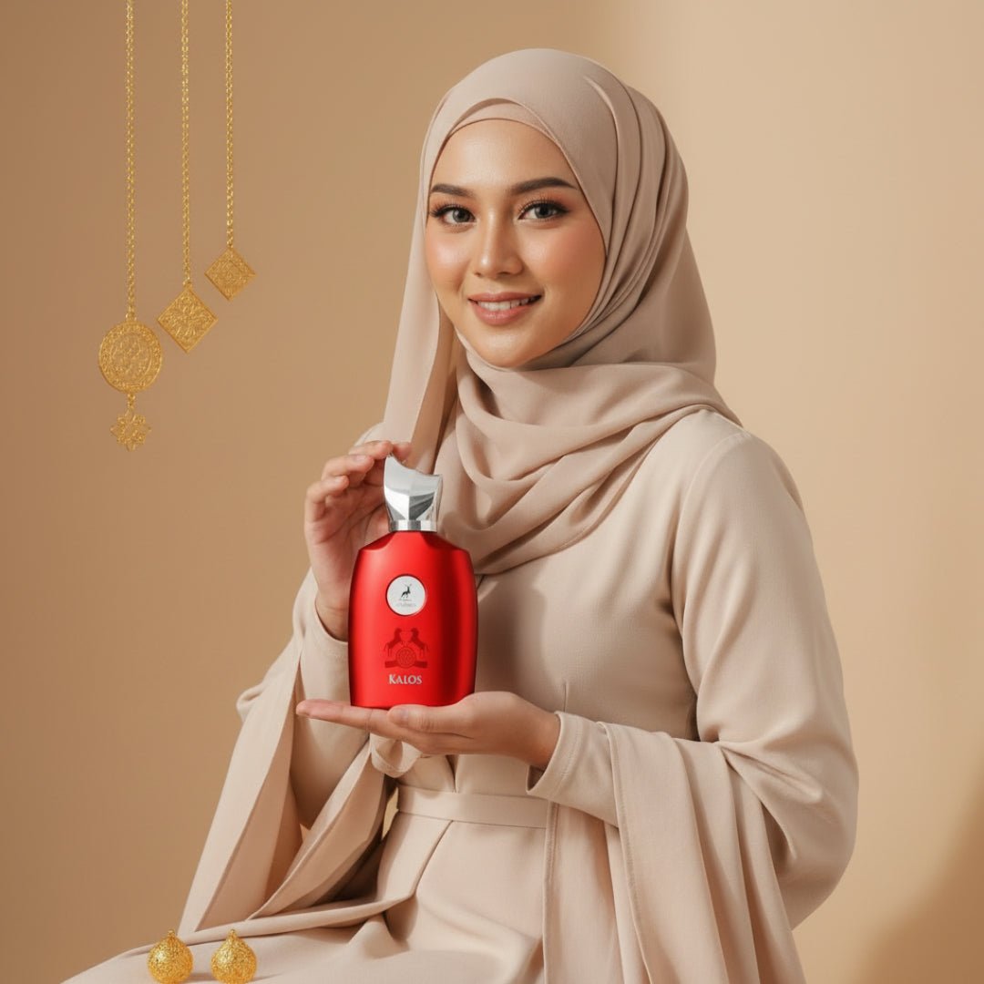 Maison Alhambra Kalos by Maison Alhambra Woman 100ml — Woman in beige hijab and dress holding a red perfume bottle with gold accents, with gold hanging ornaments and small gold baubles in the foreground. | Maison Alhambra Kalos by Maison Alhambra Woman 100ml — Wanita bertudung dan berpakaian beige memegang botol