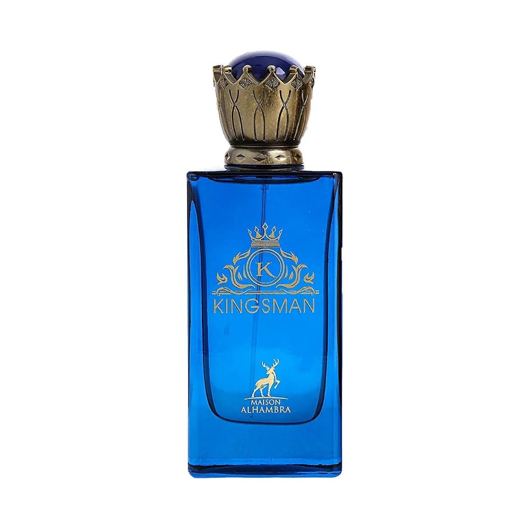 Maison Alhambra Kingsman – Blue glass perfume bottle with gold crown cap and gold emblem, next to a navy blue and gold striped box with matching emblem and deer graphic. | Maison Alhambra Kingsman – Botol minyak wangi kaca biru dengan penutup mahkota emas dan lambang emas, bersebelahan kotak berjalur biru navy dan