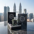 Maison Alhambra Kismet Moscow by Maison Alhambra 100ml EDP — A clear glass perfume bottle with a silver cap sits open in a black gift box lined with black satin, next to its black packaging box, with the Kuala Lumpur skyline and Petronas Twin Towers in the background. | Maison Alhambra Kismet Moscow by Maison Alhambra