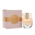Maison Alhambra La Vita EDP — Pink textured box with gold band and circular label next to a clear glass perfume bottle with gold accents and a faceted cap, showing the perfume liquid inside. | Maison Alhambra La Vita EDP — Kotak bertekstur merah jambu dengan jalur emas dan label bulat di sebelah botol minyak wangi