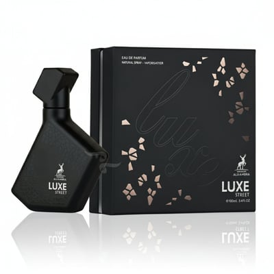 Maison Alhambra Luxe Street by Maison Alhambra – 100 ml Unisex — Black textured perfume bottle and matching black box with rose gold floral accents and text, displayed on a reflective surface. | Maison Alhambra Luxe Street by Maison Alhambra – 100 ml Unisex — Botol minyak wangi bertekstur hitam dan kotak hitam yang