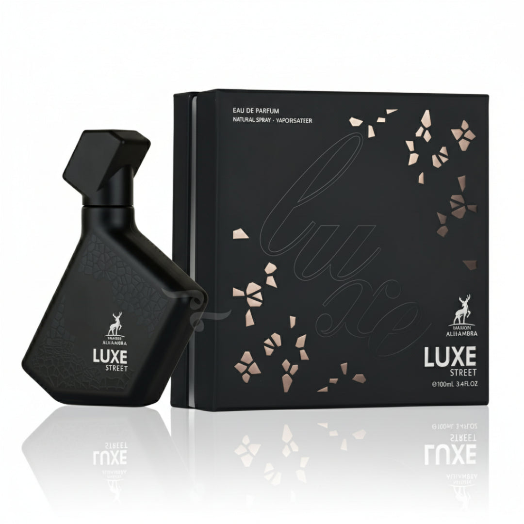 Maison Alhambra Luxe Street by Maison Alhambra – 100 ml Unisex — Black textured perfume bottle and matching black box with rose gold floral accents and text, displayed on a reflective surface. | Maison Alhambra Luxe Street by Maison Alhambra – 100 ml Unisex — Botol minyak wangi bertekstur hitam dan kotak hitam yang