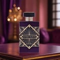 Maison Alhambra Infini Elixir Maison Alhambra 100ml EDP Men — A purple perfume bottle with a gold art deco label sits on a dark wooden surface, with a blurred opulent background of purple drapes and a chandelier. | Maison Alhambra Infini Elixir Maison Alhambra 100ml EDP Men — Botol minyak wangi ungu dengan label art