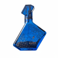 Maison Alhambra Luxe Journey – Blue glass perfume bottle with geometric patterns and gold accents, featuring a deer silhouette and the text "LUXE JOURNEY" | Maison Alhambra Luxe Journey – Botol minyak wangi kaca biru dengan corak geometri dan aksen emas, menampilkan siluet rusa dan teks "LUXE JOURNEY"