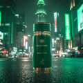 Maison Alhambra Sceptre Malachite — Green bottle with gold accents on a wet, reflective city street at night, with blurred neon lights and skyscrapers in the background. | Botol hijau dengan aksen emas di jalan bandar basah yang memantul pada waktu malam, dengan lampu neon kabur dan pencakar langit di latar belakang.