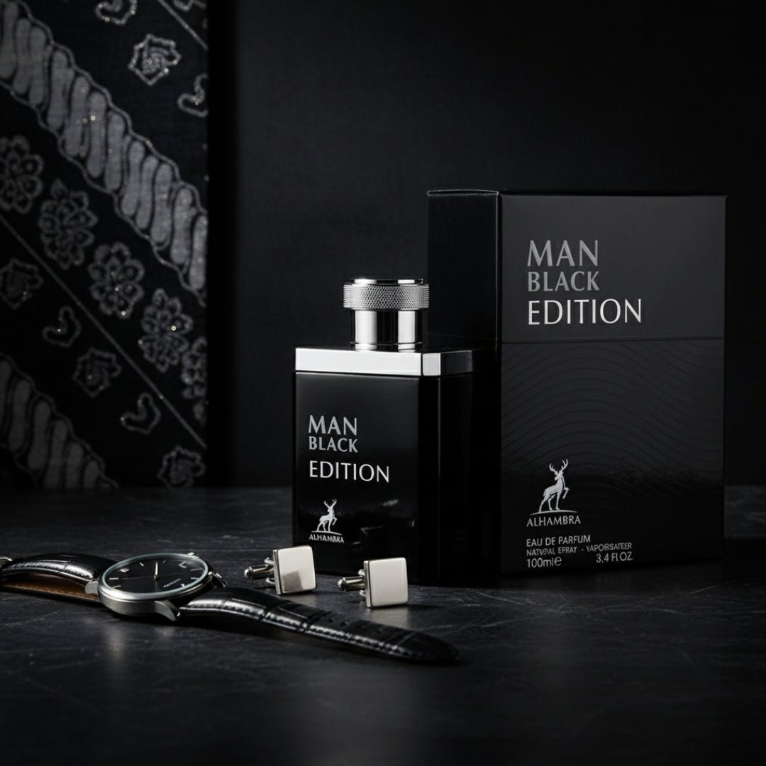 Maison Alhambra Man Black Edition — Black perfume bottle and box with silver accents, next to a watch and cufflinks on a dark textured surface, with a patterned fabric in the background. | Maison Alhambra Man Black Edition — Botol dan kotak pewangi hitam dengan aksen perak, bersebelahan jam tangan dan manset di