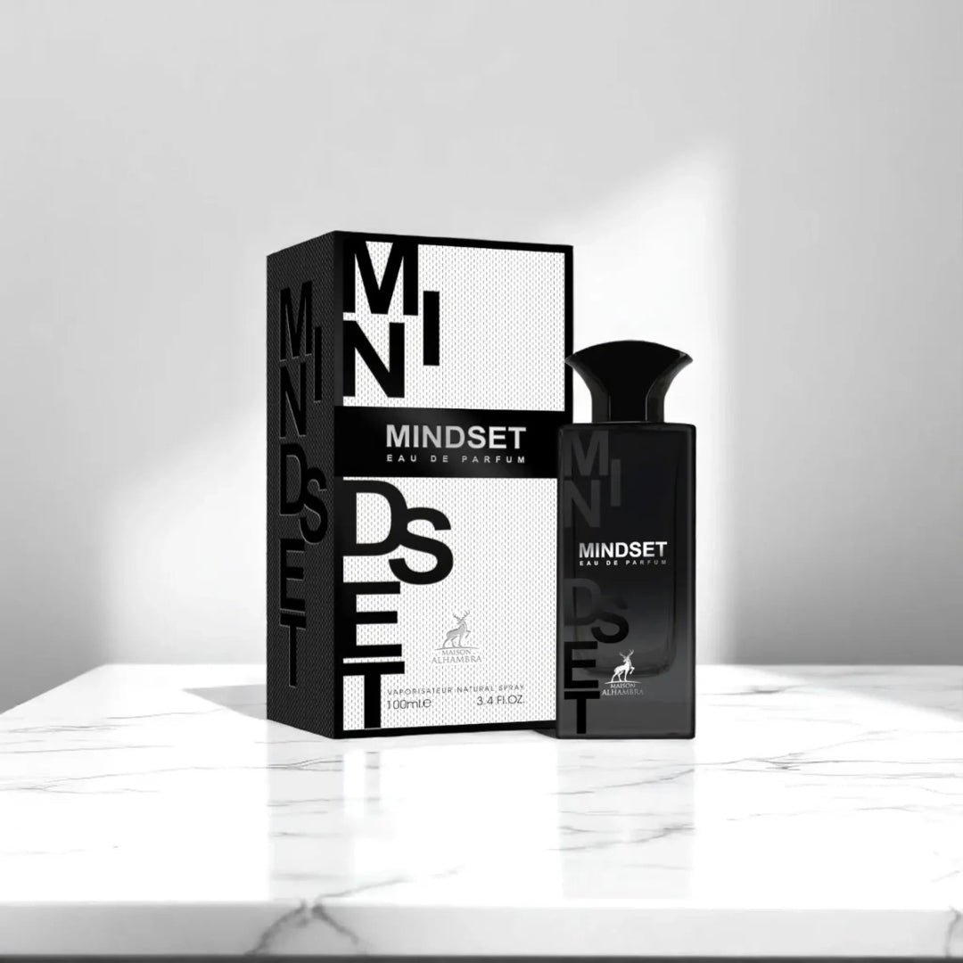 Maison Alhambra Mindset Eau de Parfum — A black perfume bottle and its white and black patterned box are displayed against a white background. The box features bold black lettering for 'MINDSET' and a deer logo. | Maison Alhambra Mindset Eau de Parfum — Botol minyak wangi hitam dan kotaknya yang bercorak hitam putih
