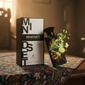 Maison Alhambra Mindset Eau de Parfum — A black perfume bottle and its white and black patterned box are displayed against a white background. The box features bold black lettering for 'MINDSET' and a deer logo. | Maison Alhambra Mindset Eau de Parfum — Botol minyak wangi hitam dan kotaknya yang bercorak hitam putih