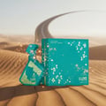 Maison Alhambra Luxe Emerald Perfume Maison Alhambra 100ml Unisex — A teal perfume bottle with gold geometric patterns sits on desert sand next to its teal box, with a winding road in the background and sparkling gold dust. | Maison Alhambra Luxe Emerald Perfume Maison Alhambra 100ml Unisex — Botol minyak wangi teal