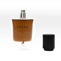 Maison Alhambra Terra – A clear glass perfume bottle with brown liquid, featuring the word "TERRA" and a deer silhouette logo at the bottom, stands next to its black wooden cap on a white background. | Maison Alhambra Terra – Botol kaca jernih berisi cecair perang, menampilkan perkataan "TERRA" dan logo siluet rusa di