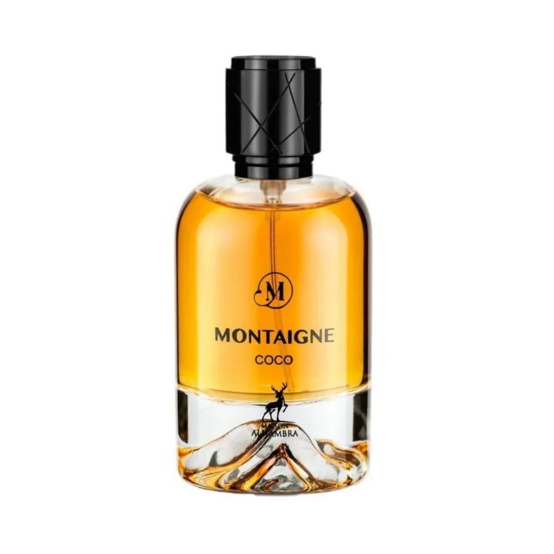 Maison Alhambra Montaigne Coco EDP — A clear glass perfume bottle with amber liquid and a black textured cap, featuring a deer silhouette and mountain-like base design. | Botol minyak wangi kaca jernih dengan cecair berwarna ambar dan penutup bertekstur hitam, menampilkan siluet rusa dan reka bentuk tapak seperti