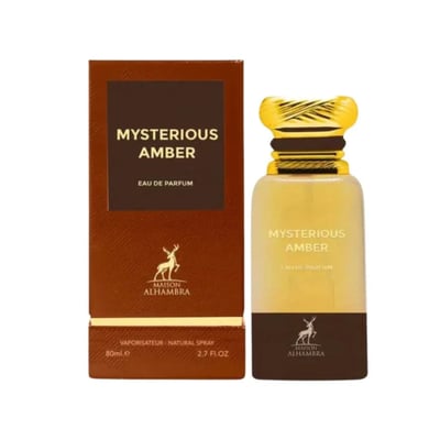 Maison Alhambra Mysterious Amber — A brown box and a clear glass bottle with a gold cap, both featuring the product name and brand logo. | Maison Alhambra Mysterious Amber — Kotak coklat dan botol kaca jernih dengan penutup emas, kedua-duanya memaparkan nama produk dan logo jenama.