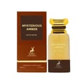 Maison Alhambra Mysterious Amber — A brown box and a clear glass bottle with a gold cap, both featuring the product name and brand logo. | Maison Alhambra Mysterious Amber — Kotak coklat dan botol kaca jernih dengan penutup emas, kedua-duanya memaparkan nama produk dan logo jenama.