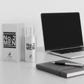 Maison Alhambra No.2 Men by Maison Alhambra 80ml EDP — A silver perfume bottle and its matching box sit on a desk next to a laptop and a notebook with a pen. | Maison Alhambra No.2 Men by Maison Alhambra 80ml EDP — Botol minyak wangi perak dan kotak padanannya diletakkan di atas meja bersebelahan komputer riba dan