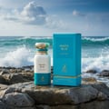 Maison Alhambra Pacific Blue — A white and teal perfume bottle and its teal box sit on wet rocks with ocean waves crashing in the background. | Maison Alhambra Pacific Blue — Sebotol dan kotak minyak wangi putih dan teal duduk di atas batu basah dengan ombak lautan berderu di latar belakang.