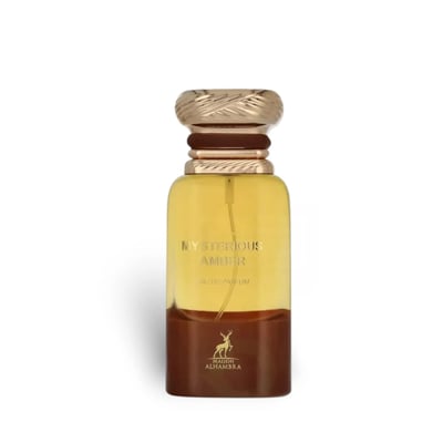 Maison Alhambra Mysterious Amber — A brown box and a clear glass bottle with a gold cap, both featuring the product name and brand logo. | Maison Alhambra Mysterious Amber — Kotak coklat dan botol kaca jernih dengan penutup emas, kedua-duanya memaparkan nama produk dan logo jenama.