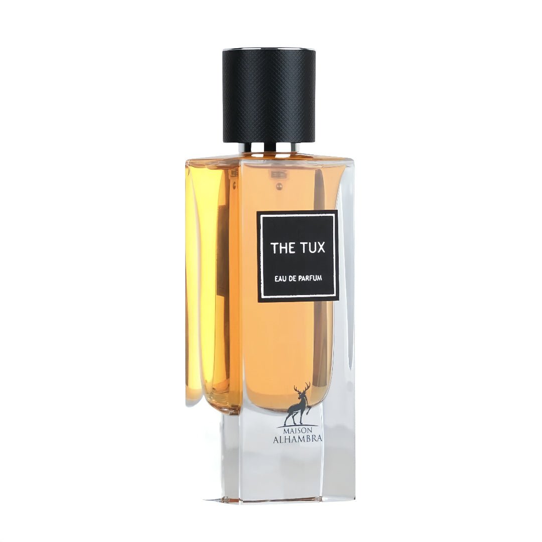 Maison Alhambra The Tux by Maison Alhambra 90ml EDP for Men — A clear glass perfume bottle with amber liquid, a black textured cap, and a black label with white text reading 'THE TUX EAU DE PARFUM' and a deer silhouette logo. | Maison Alhambra The Tux by Maison Alhambra 90ml EDP for Men — Botol kaca jernih berisi