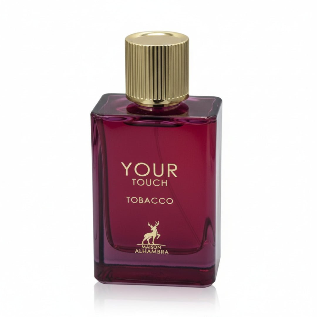 Maison Alhambra Tobacco Your Touch — A rectangular, deep red glass perfume bottle with a fluted gold cap, featuring gold text 'YOUR TOUCH TOBACCO' and a deer logo | Maison Alhambra Tobacco Your Touch — Botol kaca berwarna merah pekat berbentuk segi empat dengan penutup emas berlubang, menampilkan teks emas 'YOUR TOUCH