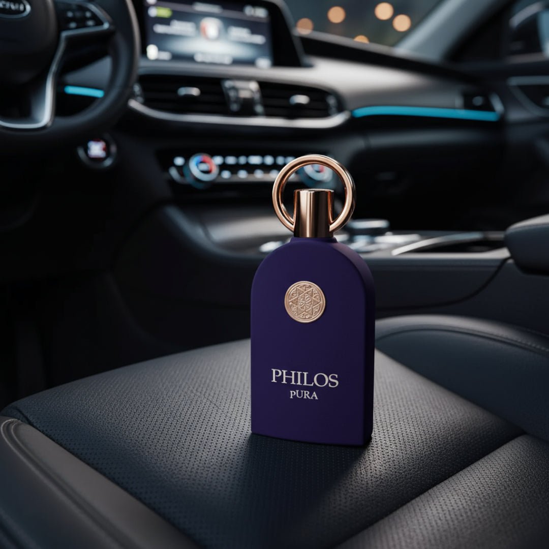 Maison Alhambra Philos Pura by Maison Alhambra 100ml EDP Man — A dark purple perfume bottle with a gold ring and emblem sits on a black leather car seat, with the car's dashboard and steering wheel blurred in the background. | Botol minyak wangi ungu gelap dengan cincin dan lambang emas duduk di atas tempat duduk
