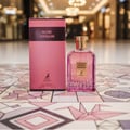 Maison Alhambra Rose Origami — A pink perfume box and a clear glass bottle with pink liquid and a gold cap sit on a colorful tiled surface with origami crane designs. | Maison Alhambra Rose Origami — Kotak minyak wangi merah jambu dan botol kaca jernih dengan cecair merah jambu dan penutup emas diletakkan di atas