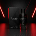 Maison Alhambra Salvo by Maison Alhambra For Him 100ml — A black perfume bottle and its matching box stand on a dark, textured surface, illuminated by dramatic red neon lights against a carbon fiber-like background. | Maison Alhambra Salvo by Maison Alhambra For Him 100ml — Botol minyak wangi hitam dan kotaknya yang